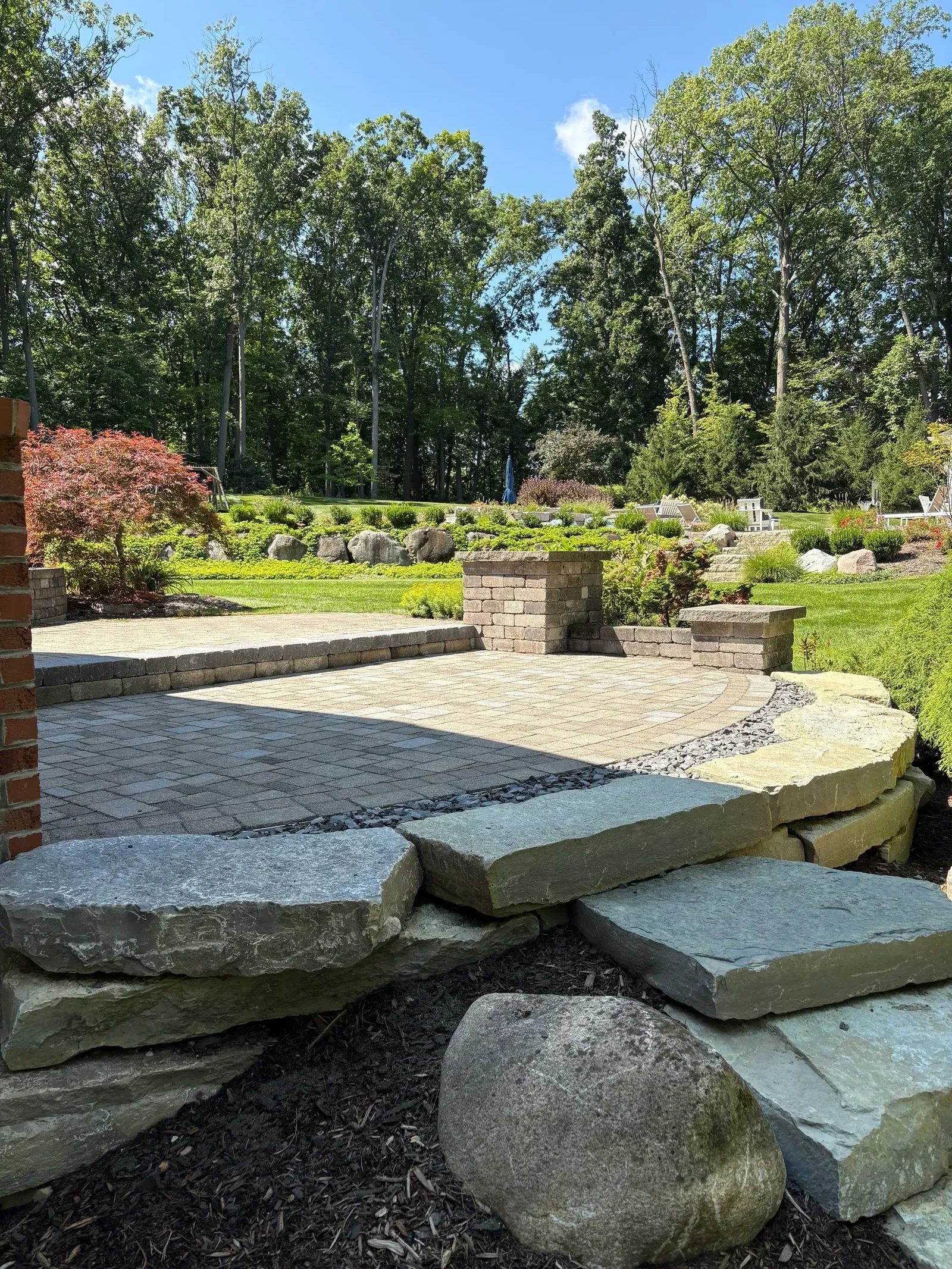 Paver patio with tumbled stone pavers and stacked slate retaining wall in residential landscape