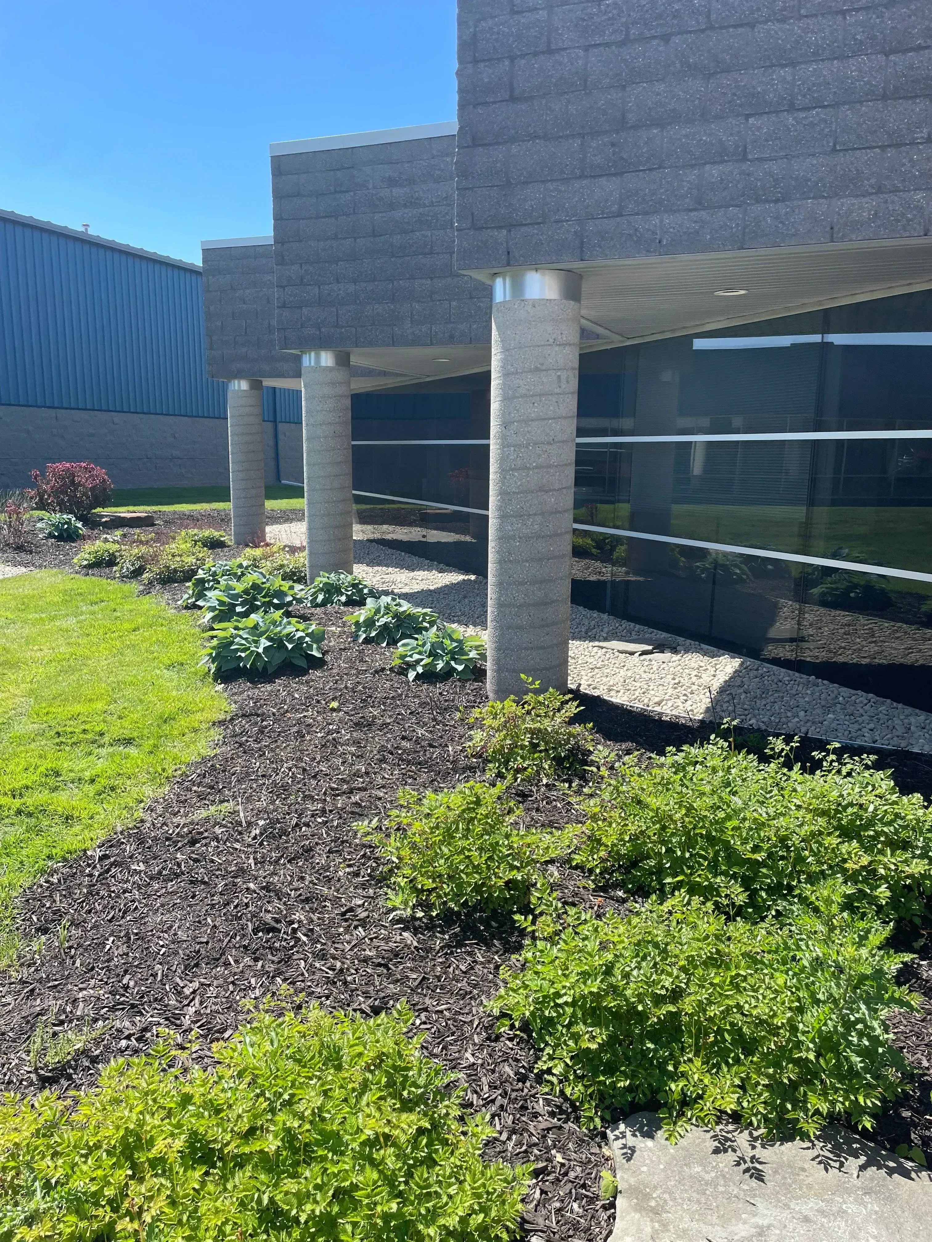 Composite deck with metal railings, mulched planter beds, and manicured shrubs