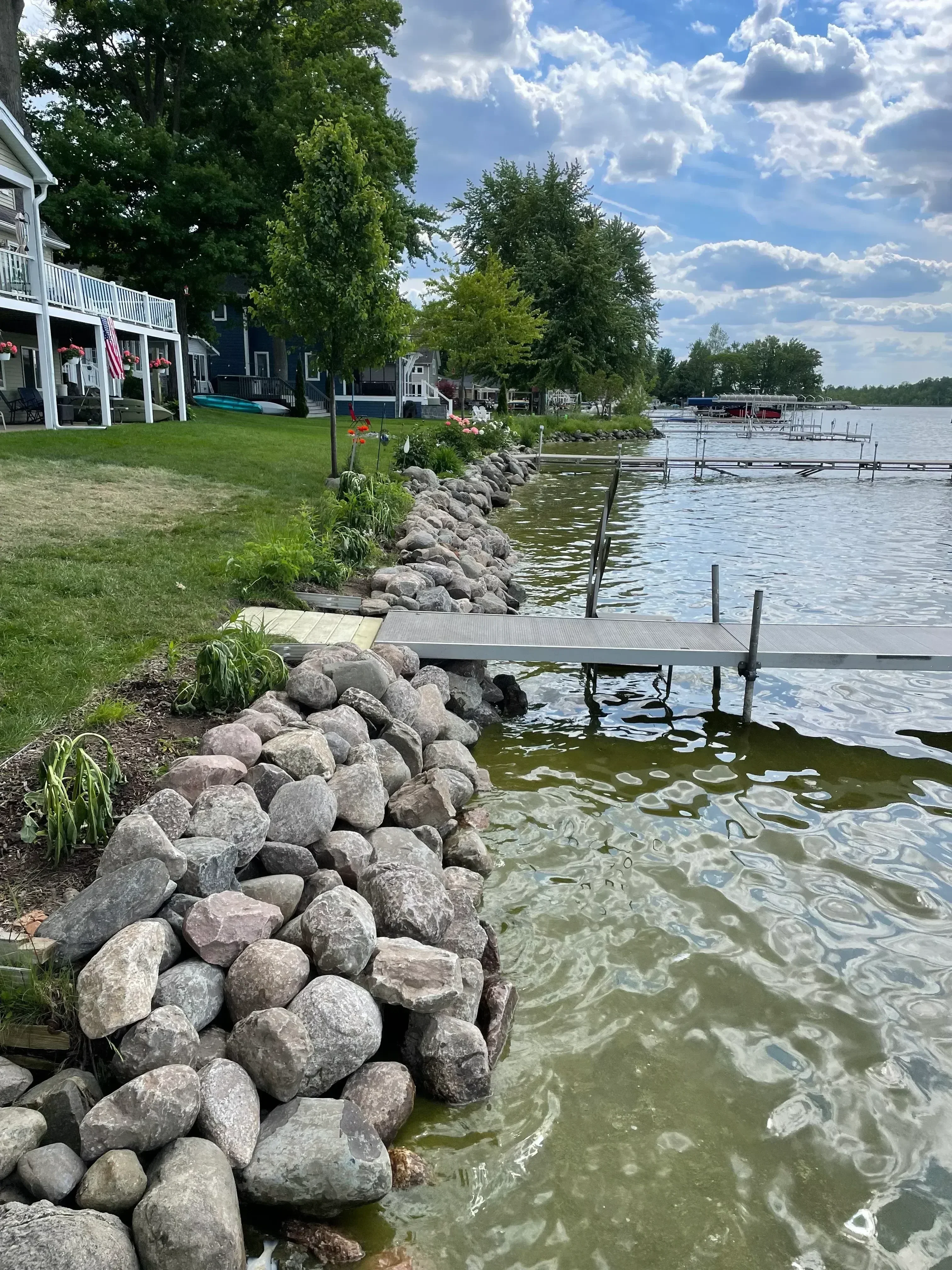 Granite riprap boulders installed along waterfront with wooden dock and metal railings