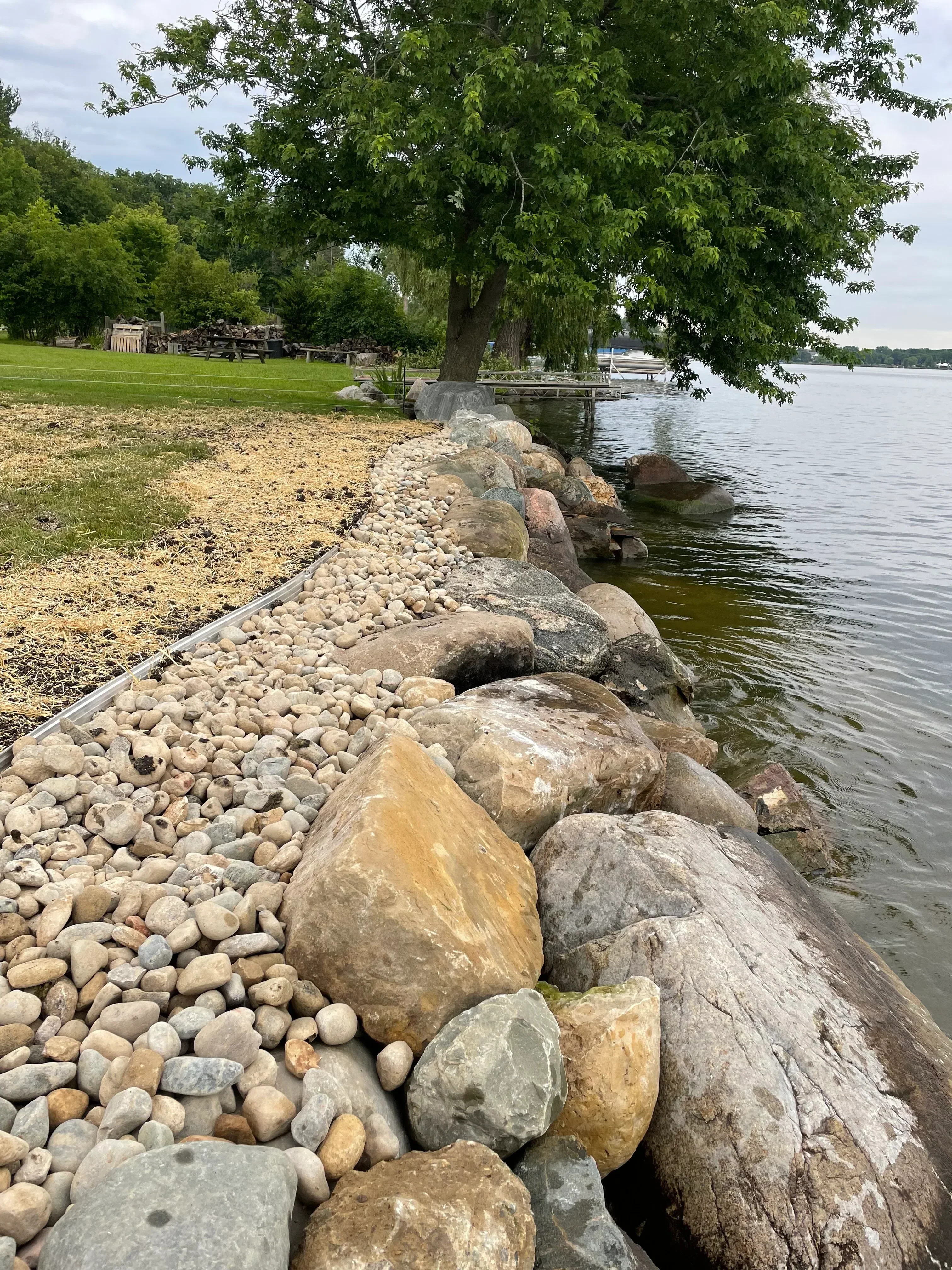 Stacked riprap boulders and river stone erosion control along waterfront embankment