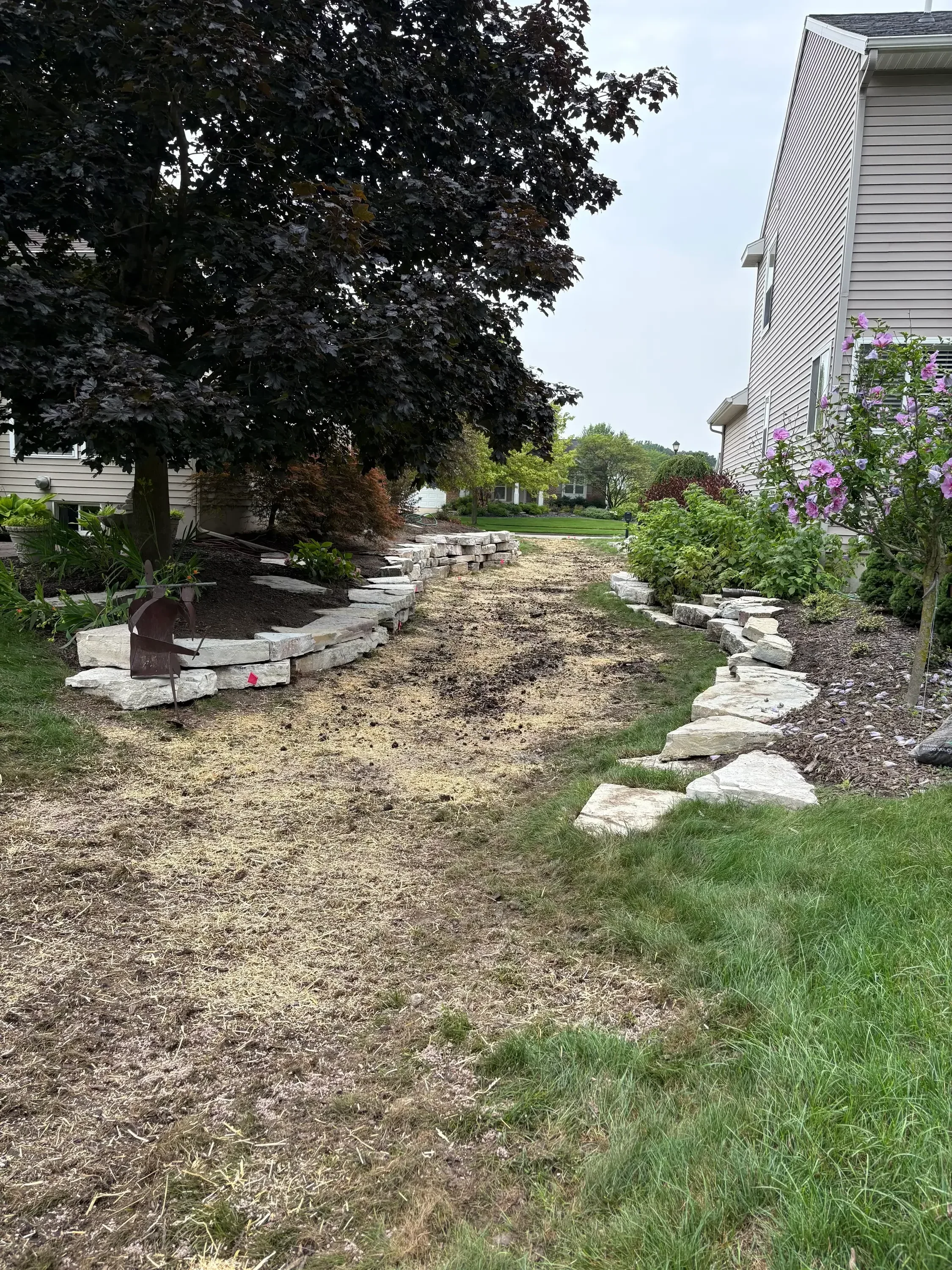 Concrete block retaining wall with drainage, green lawn, and flowering plants